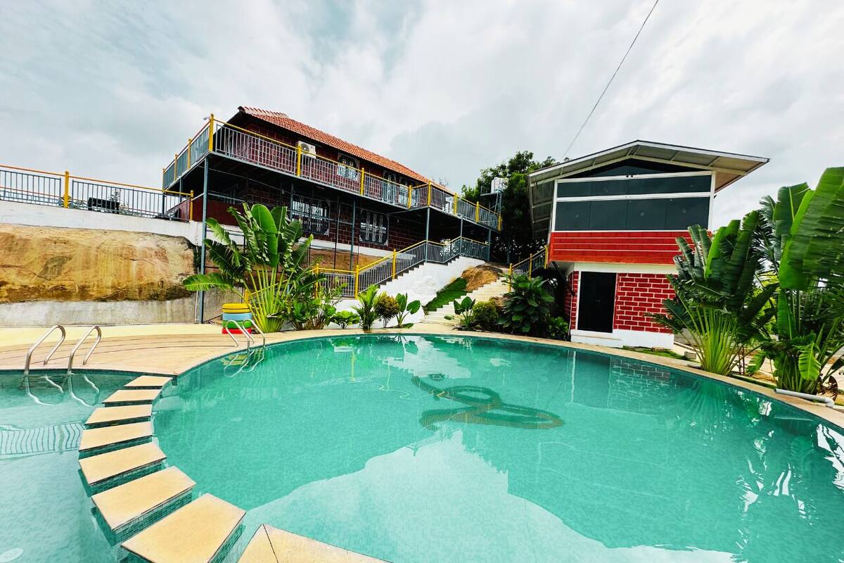 Una piscina con escalones de acceso, rodeada de vegetación y edificios.
