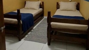 A room with two wooden beds, a blue wall, and nautical-themed decorations including a boat and an anchor. - Quintal do Mar Hostel (Salvador)