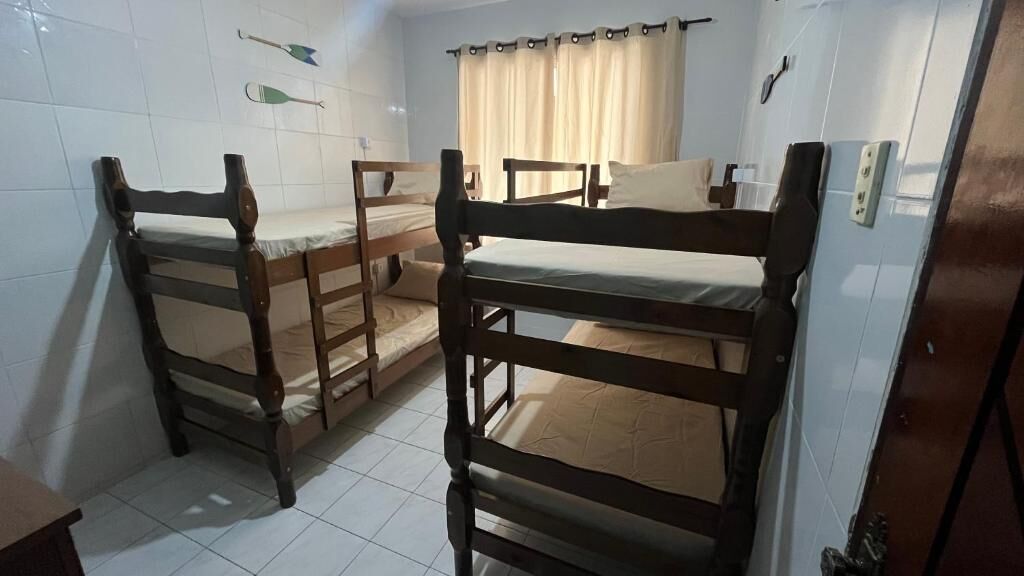 A room with three wooden bunk beds, a small table, and a curtain.