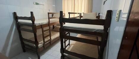 A room with three wooden bunk beds, a small table, and a curtain.