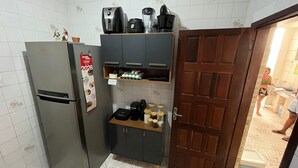 A compact kitchen with a refrigerator, a coffee maker, a blender, and a shelf with jars. - Quintal do Mar Hostel (Salvador)