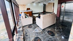 En modern hotellobby med en receptionsdisk, en sittgrupp och ett golv av marmor.