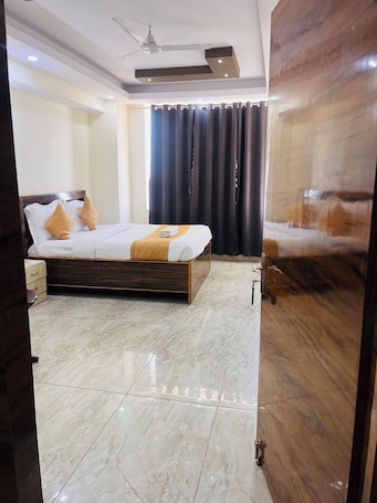 A modern hotel room with a large bed, a ceiling fan, and a view of the outdoors.. Hotel Maple inn and Banquet