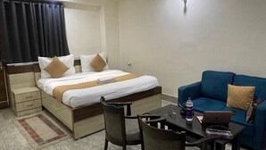 Ett hotellrum med en säng, en blå soffa, ett matbord med stolar och en bärbar dator.