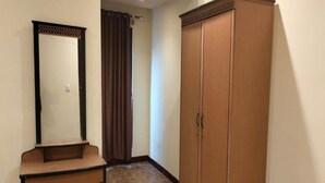 A room with a wooden wardrobe, a mirror, and a herringbone-patterned floor. - Cozzy Galaxy Hotel (Manado)