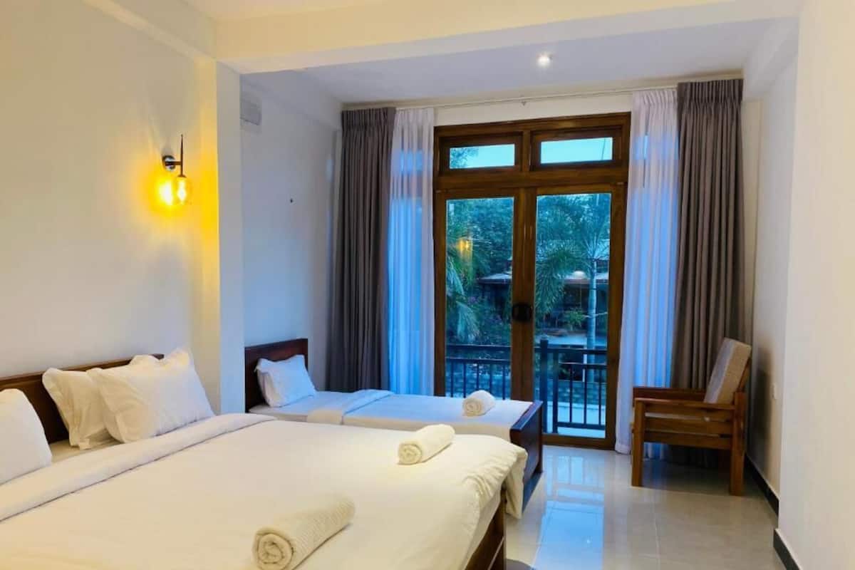 Habitación de hotel con dos camas, un balcón y una silla.