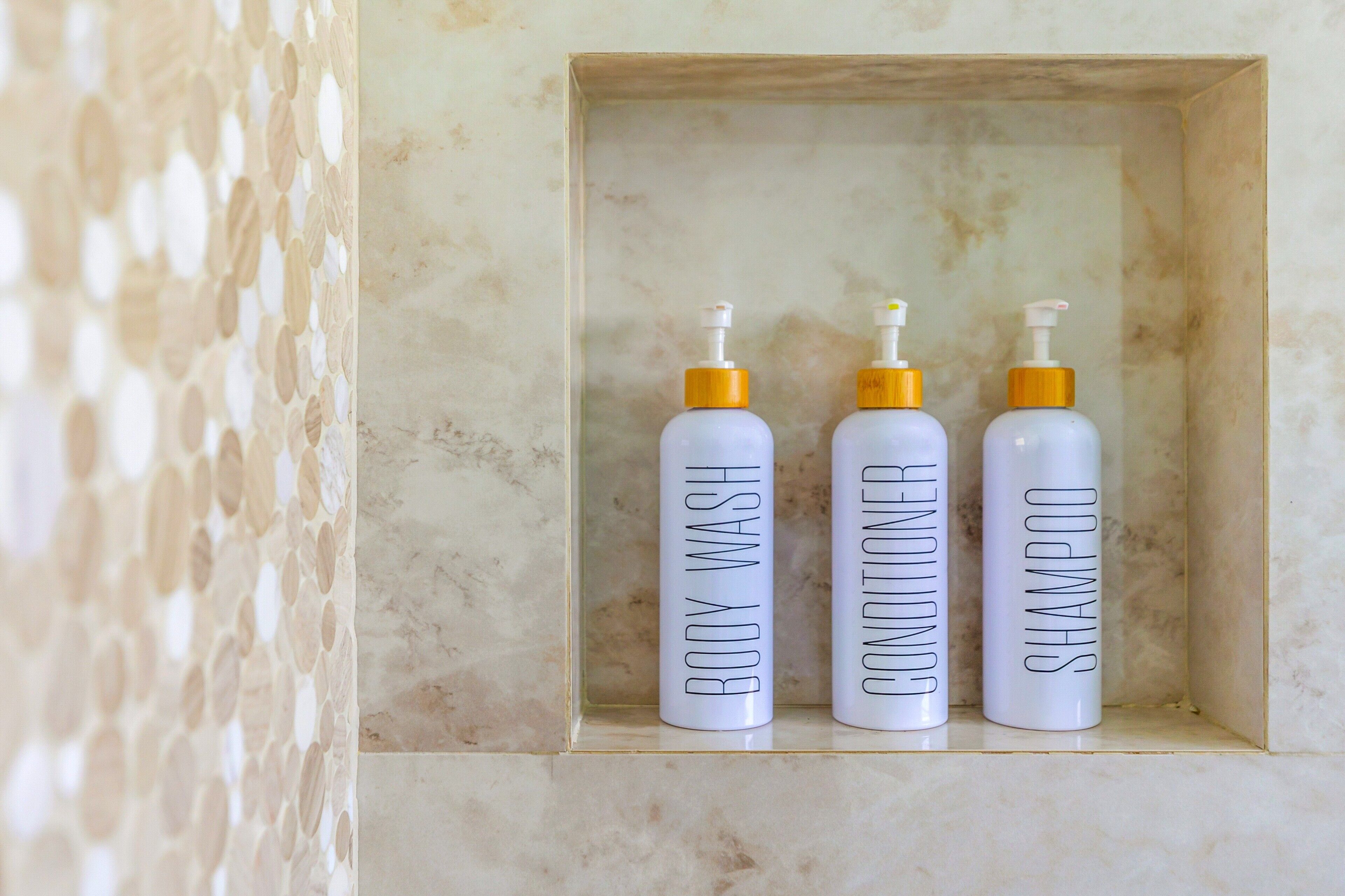 Three bottles of body wash, conditioner, and shampoo in a wooden box.