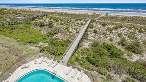 Un complex turístic a la vora de la platja amb un llarg moll, una piscina i accés directe a la sorra.
