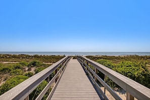 Una pasarela de madera que conduce a una playa con cielos despejados.