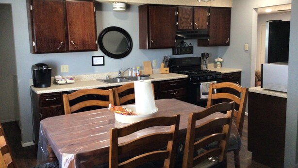 Una cocina con armarios de madera, estufa, lavaplatos y una mesa de comedor con sillas.