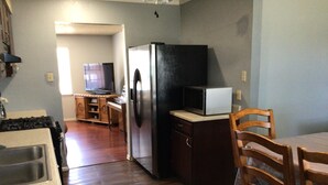 Una cocina con refrigerador, microondas y armarios de madera.