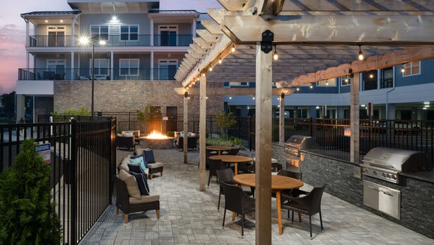 An outdoor patio with seating, a fire feature, and a barbecue area. - NEW Designer Coastal Condo - Sleeps 8 -Close to Downtown Rehoboth Next to Dining (Rehoboth Beach)