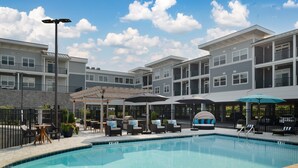 A pool area with lounge chairs, umbrellas, and a covered seating area. - NEW Designer Coastal Condo - Sleeps 8 -Close to Downtown Rehoboth Next to Dining (Rehoboth Beach)
