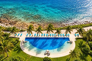 Un complexe hôtelier doté d’une grande piscine, de palmiers et d’une plage.