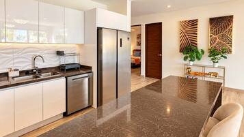 Una cocina moderna con un refrigerador de acero inoxidable, lavavajillas y encimera de mármol.