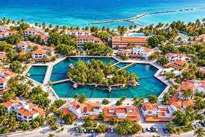 A resort with multiple buildings, a central pool area, and a surrounding beach. - Canal view, pool, 7-min walk to beach (Puerto Aventuras)