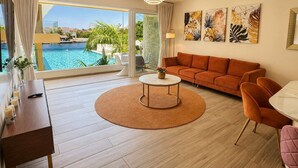A modern living room with a sofa, coffee table, and chairs, large windows with a pool view, and artwork on the wall. - Canal view, pool, 7-min walk to beach (Puerto Aventuras)
