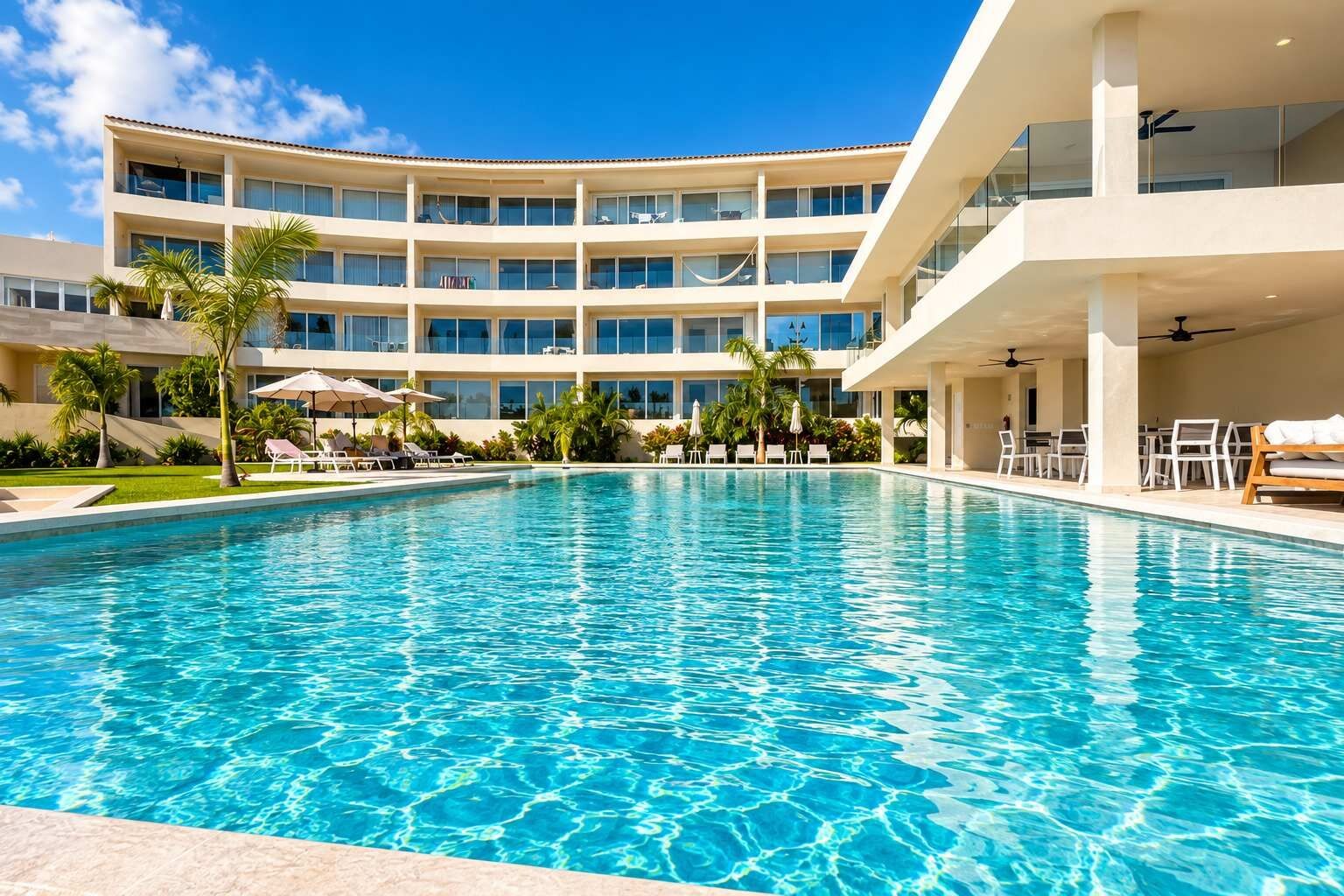 Um hotel com uma piscina grande, várias varandas e áreas de estar ao ar livre.