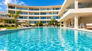 Um hotel com uma piscina grande, várias varandas e áreas de estar ao ar livre.