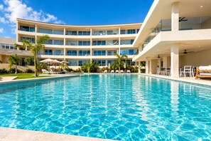Um hotel com uma piscina grande, várias varandas e áreas de estar ao ar livre.