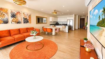 Uma sala de estar moderna com um sofá, uma mesa de centro redonda e um espaço de refeições com cadeiras.