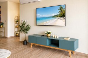 Una sala de estar moderna con una consola color turquesa, una fotografía grande enmarcada de una playa y una planta en maceta.