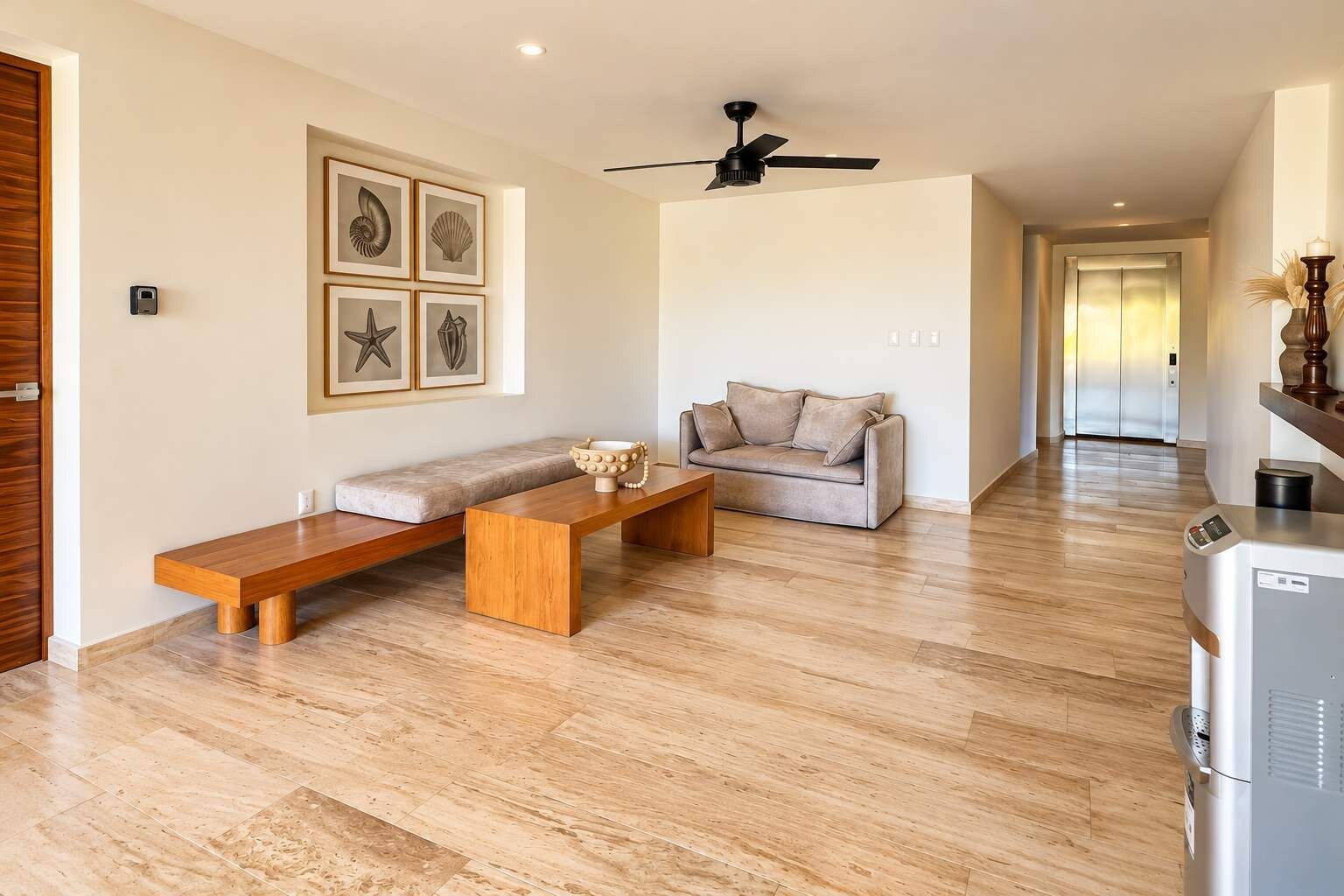 Een moderne woonkamer met een bank, een houten zitbank en een salontafel. Er is een plafondventilator en een koelkast in de kamer.