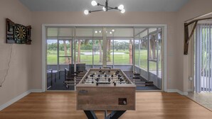 A room with a foosball table, a dartboard, and a chandelier. - Sunset Palms, lake view-Near manatees, golf & scalloping (Crystal River)