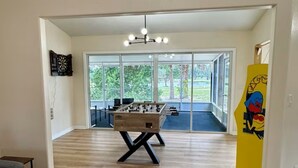 A spacious room with a foosball table, a sofa, and a large window offering a view of the outdoors. - Sunset Palms, lake view-Near manatees, golf & scalloping (Crystal River)