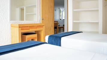 Una habitación con dos camas, un escritorio de madera, un espejo y una silla.