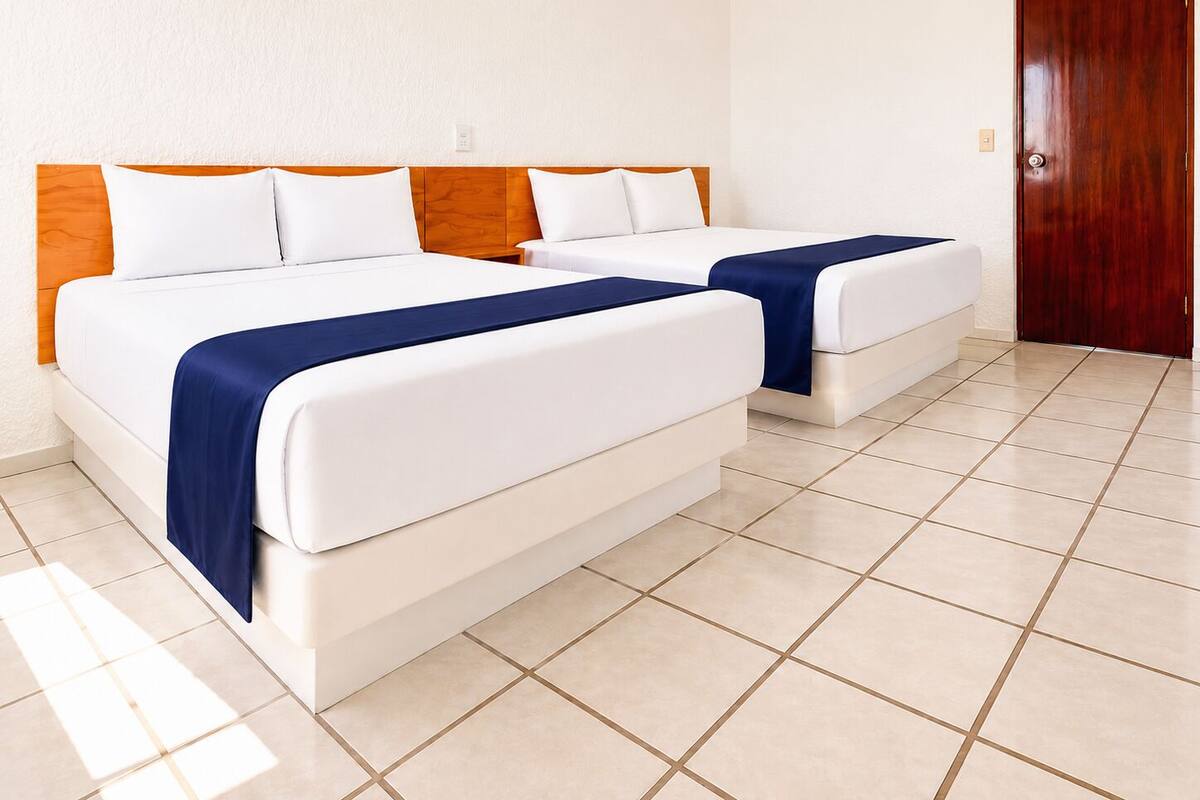 Habitación de hotel con dos camas, cabecero de madera y piso de baldosas.