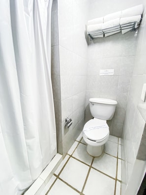 Pieni, siisti kylpyhuone, jossa on wc, pyyheteline ja suihkuverho.