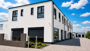 A modern building with a flat roof, large windows, and a paved entrance area. - Comfortable Premium Business Apartment Darmstadt-Griesheim Including parking space (Griesheim)