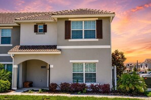 A two-story residential building with a tiled roof, a front entrance with a door number, and a small porch area. - Storey Lake 5BR | Private Pool | Resort Water Park | Near Disney (Kissimmee)