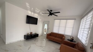 Una sala de estar con televisor de pantalla plana, ventilador de techo, sofá y mesa de centro.
