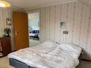 A bedroom with a bed, a dresser, a fan, and a door leading to another room. - 5 Person Holiday Home in Emmaboda (Emmaboda)