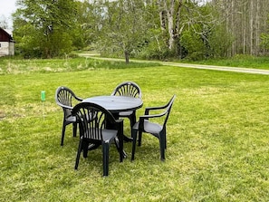 A round table with four chairs in a grassy outdoor area with trees in the background. - 5 Person Holiday Home in Emmaboda (Emmaboda)