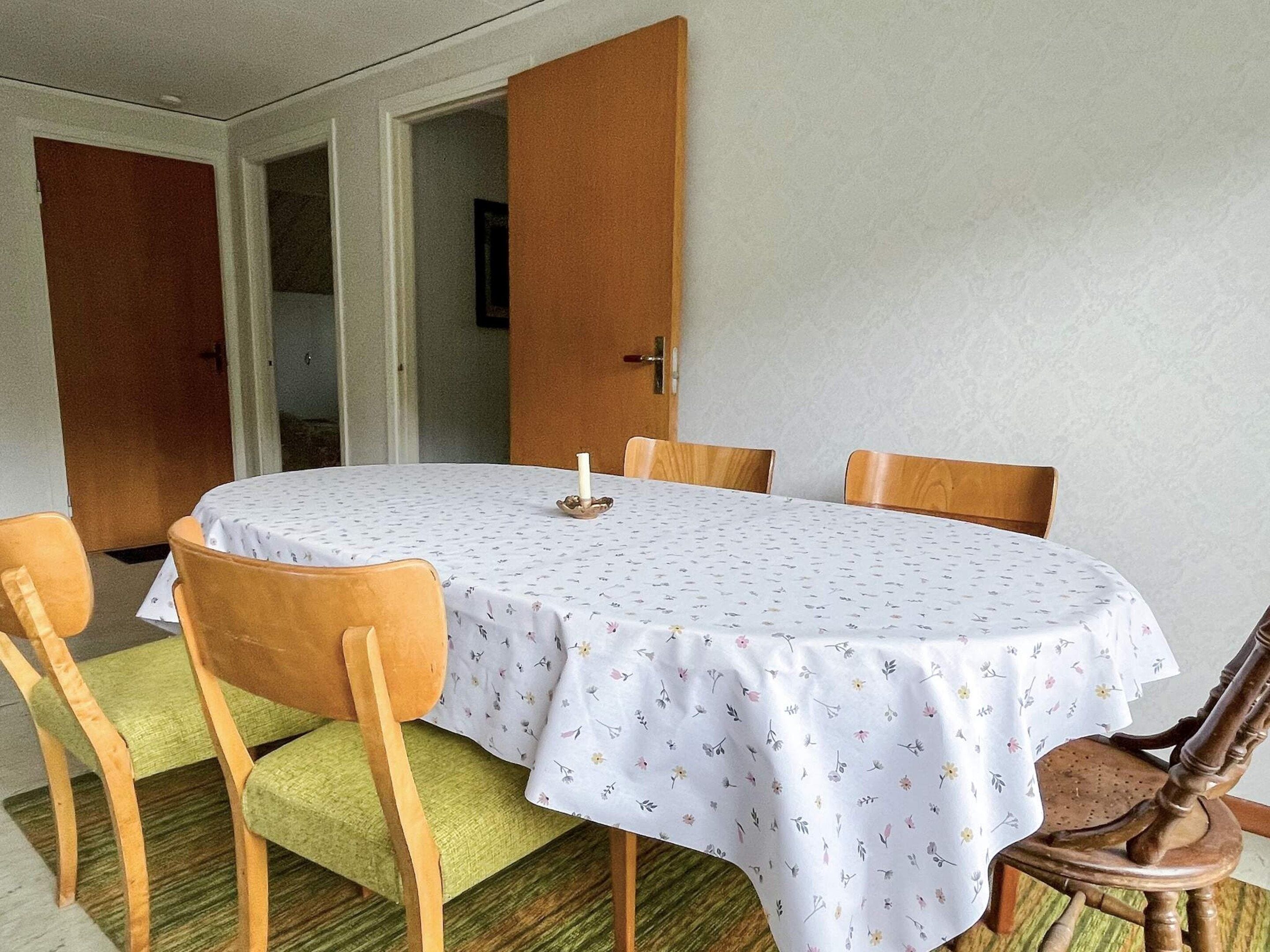 A dining area with a round table, four chairs, and a door leading to another room.