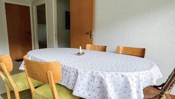A dining area with a round table, four chairs, and a door leading to another room.