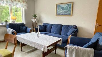 A room with a blue sofa, a wooden table, and a painting on the wall.