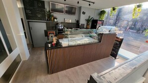 En kaffebutiks interiör med en disk, en menytavla och ett område med sittplatser.