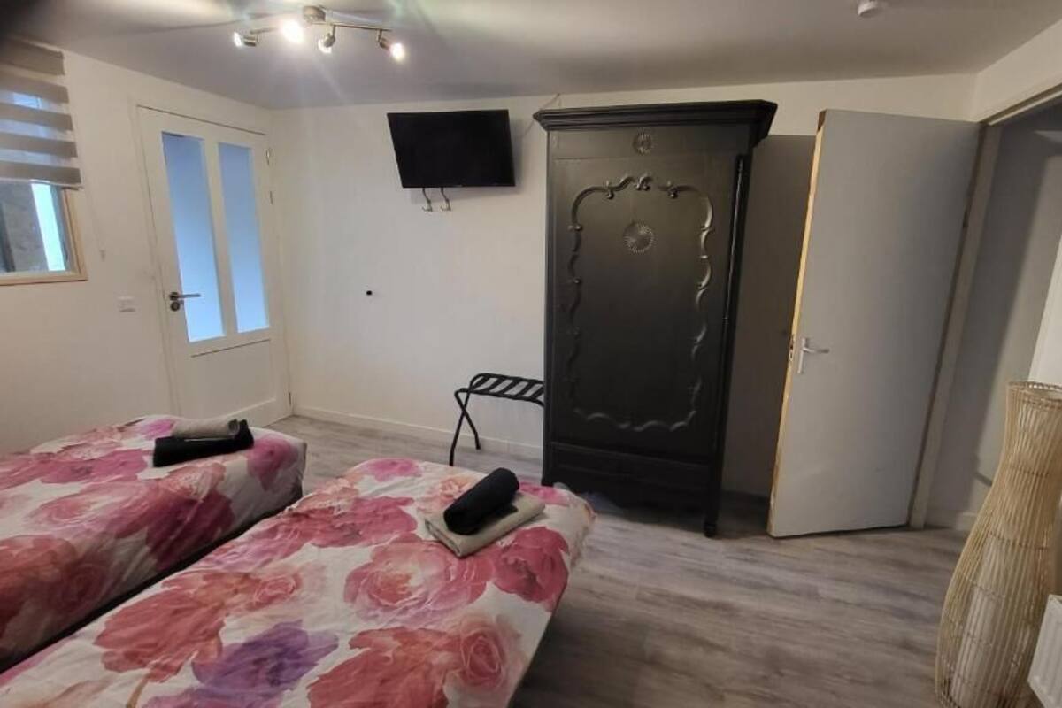 Quarto com duas camas, um guarda-roupa, uma televisão e uma janela.