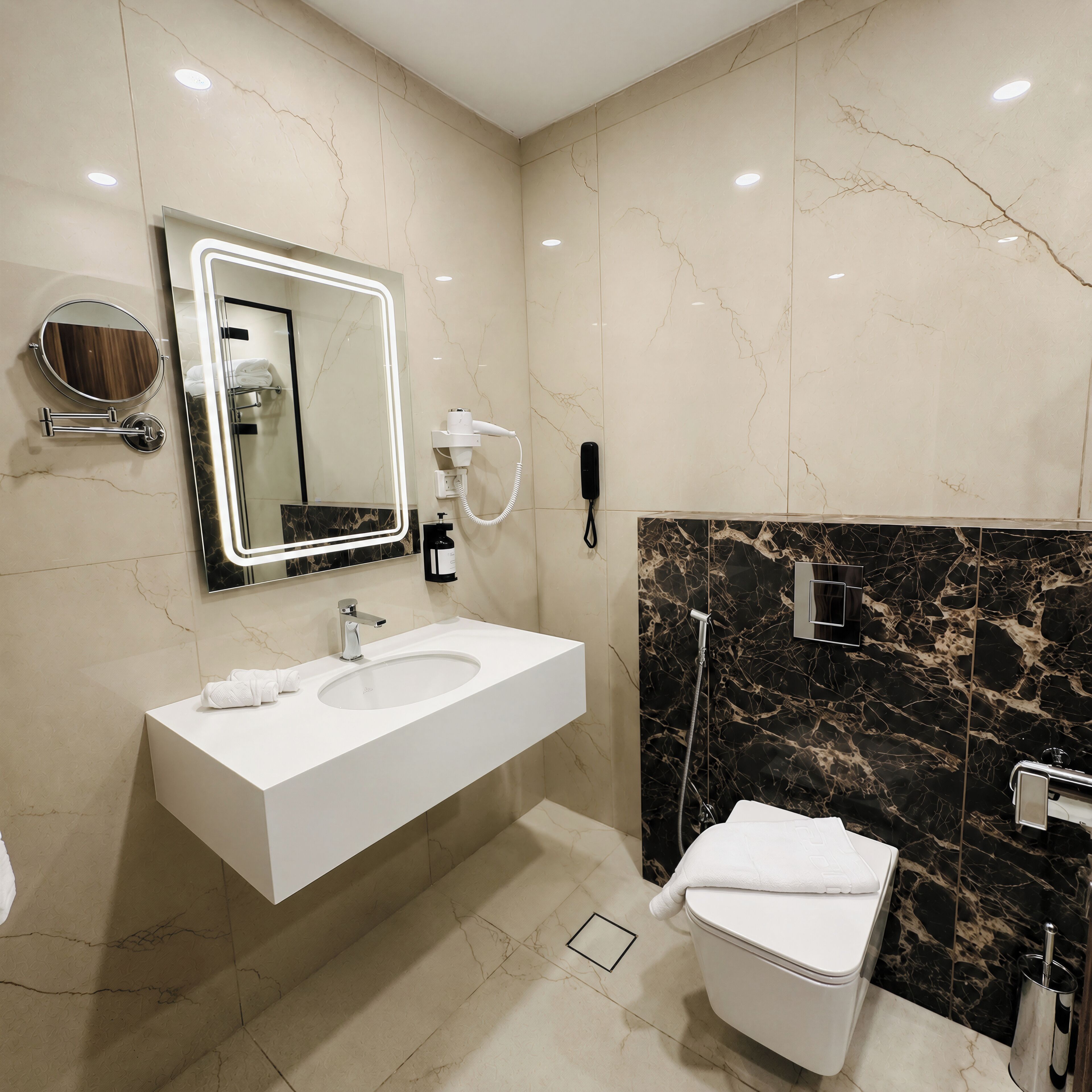 Un baño moderno con lavamanos blanco, espejo, secador de pelo y retrete.