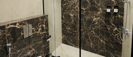 A modern bathroom with a glass-enclosed shower, a toilet, and marble walls.