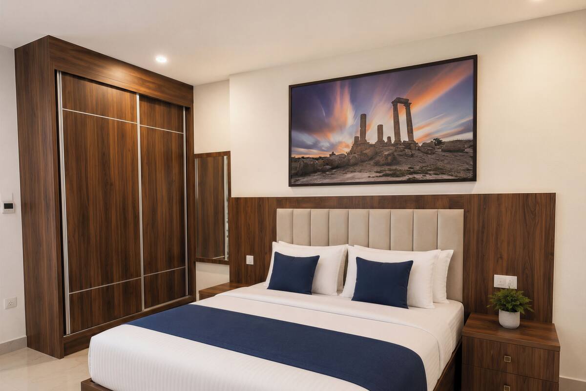 Un dormitorio con una cama grande, un armario de madera y un cuadro de ruinas antiguas.