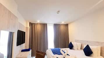 Ein Hotelzimmer mit Bett, Schreibtisch, Stuhl, Fernseher und Vorhängen.