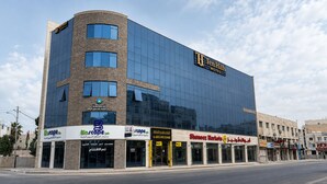 Un hôtel moderne à la façade en verre, avec une enseigne BioScope et des magasins Shoneez.
