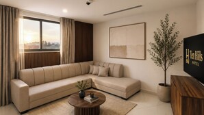 Un salon moderne avec un canapé d’angle, une table basse, une plante en pot et un téléviseur.