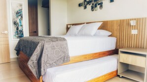 A double bed with a wooden frame and a grey patterned bedspread, a bedside table, and a wall-mounted light fixture. - Baia Kristal Experience Apartment (Cartagena)