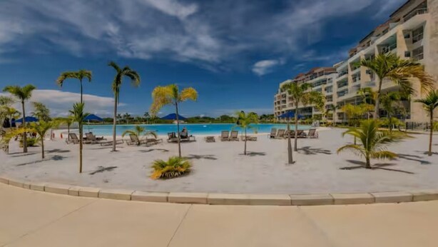 A resort pool area with lounge chairs and palm trees. - Baia Kristal Experience Apartment (Cartagena)